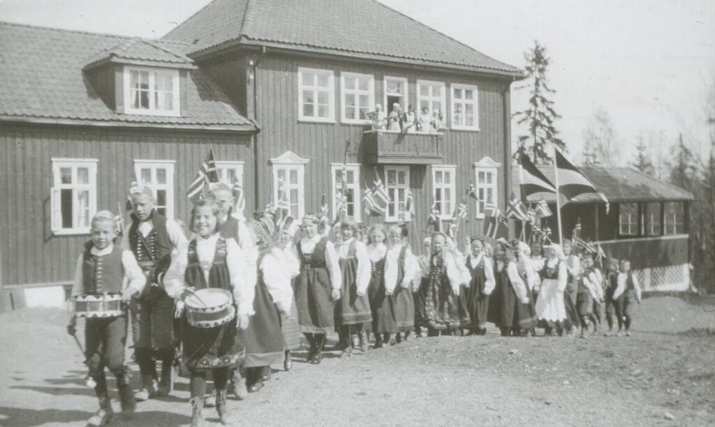 svart-hvitt bilde av 17mai tog foran skolen